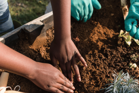 A close-up of a farmer guiding a kid in worm farming