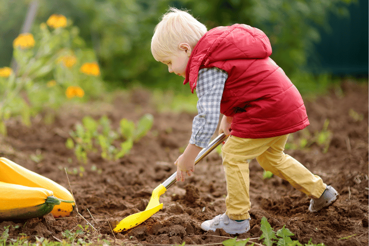 A kid playing farmer and shoveling beds