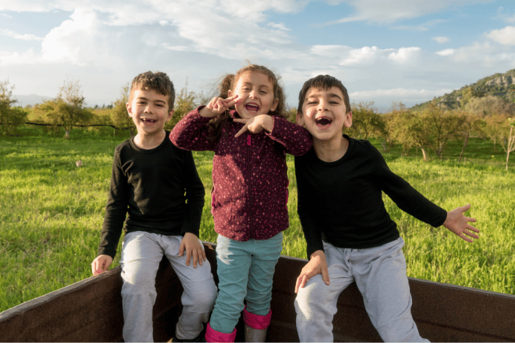 Three children on the back of a farm truck