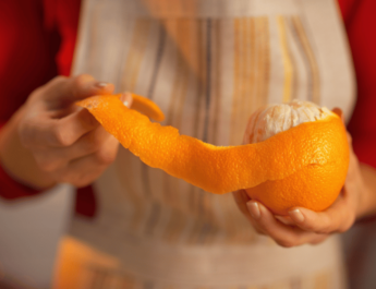 Close-up of woman removing orange peel